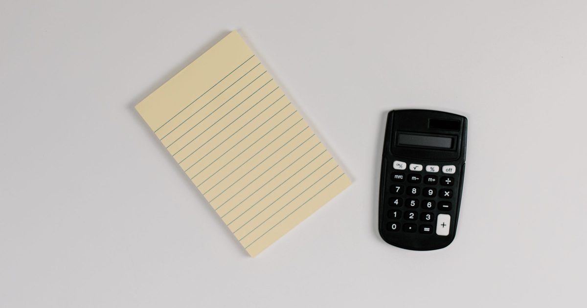 Calculator and a blank lined notepad on a gray desk